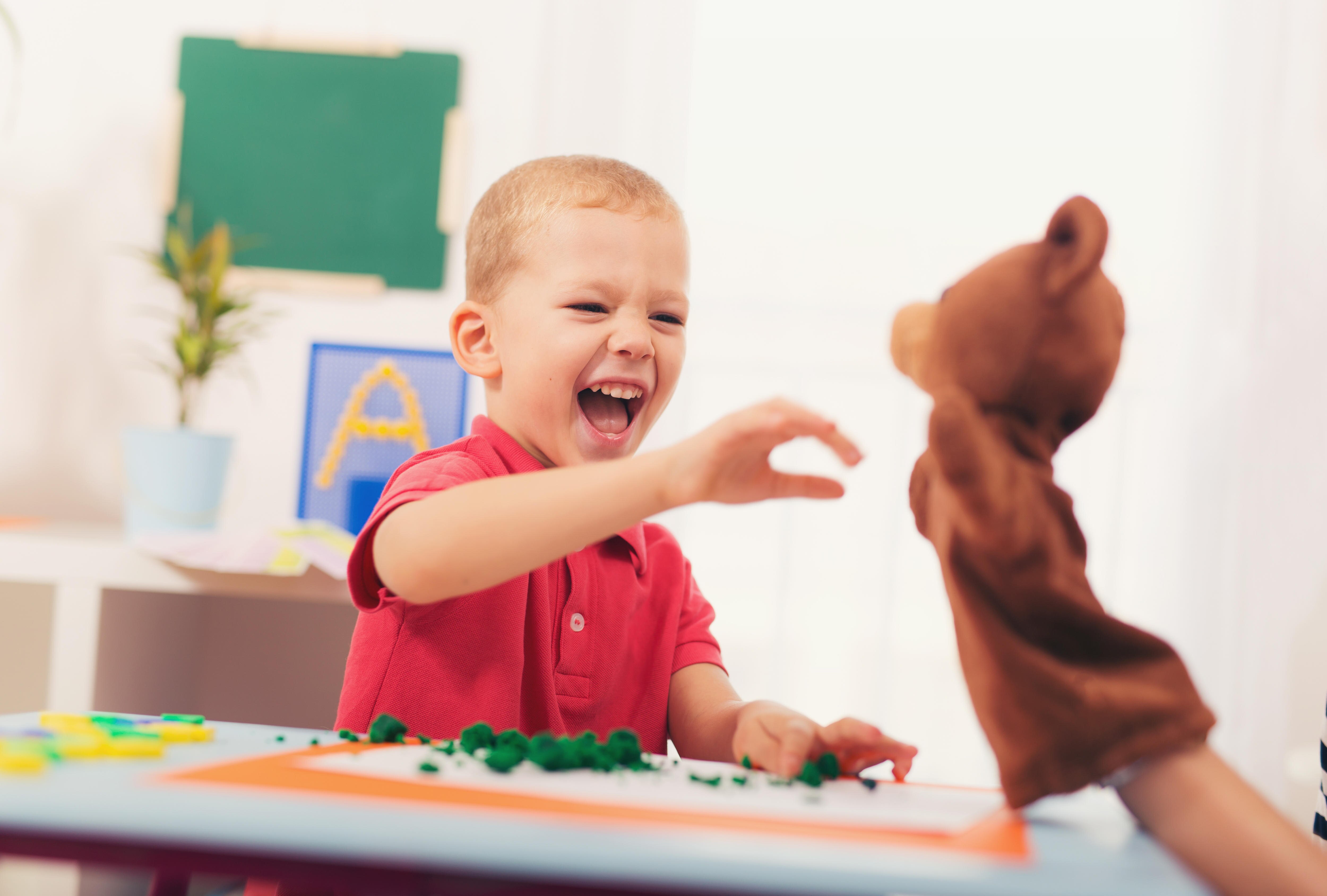 A young boy plays with a sock puppet. 