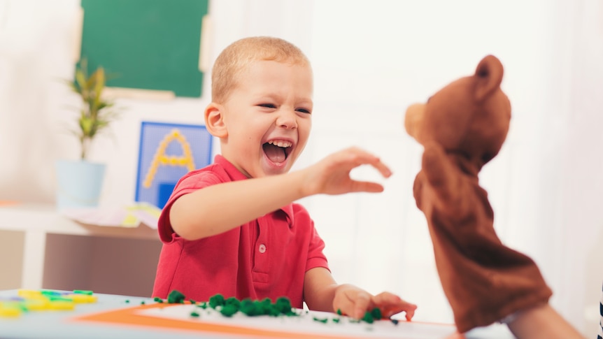 A young boy plays with a sock puppet. 