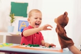 A young boy plays with a sock puppet. 