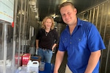 Dr Amina Price and Zac Rolfe stand at the front of a shipping container with fish tanks behind them