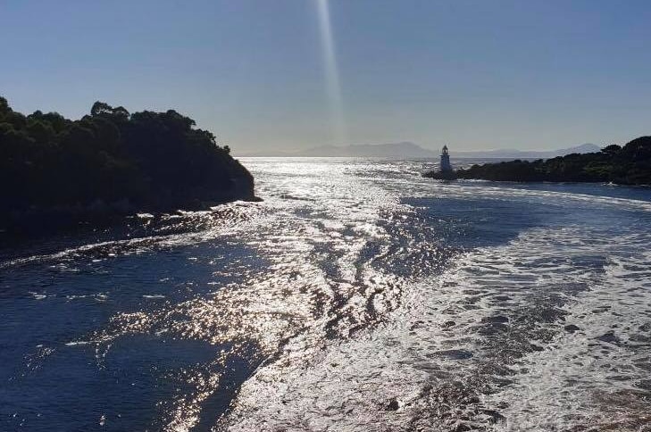 View of the wake of a passenger craft as it passes through the narrow channel of water.