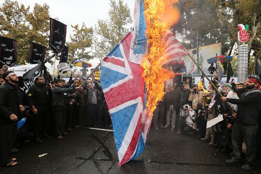 Iranian protesters burn British and US flag.
