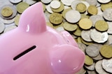 A piggy bank sits on a pile of Australian coins.
