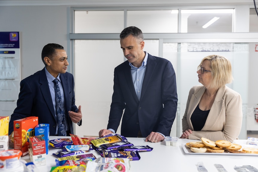 Two men and a woman looking a food products