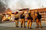 A group of firemen watch a house burn