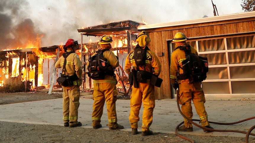 A group of firemen watch a house burn