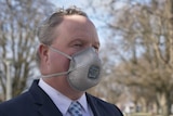 A man in a suit wearing a face mask.
