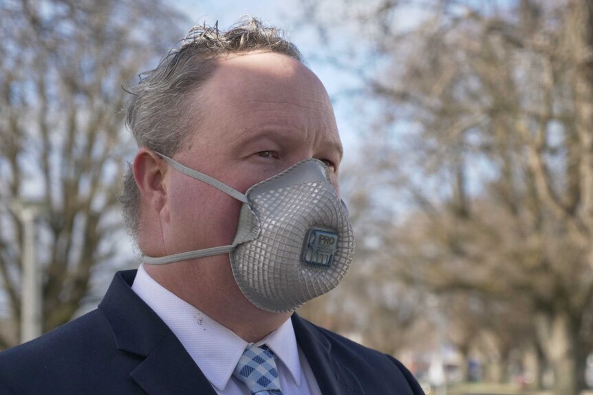 A man in a suit wearing a face mask