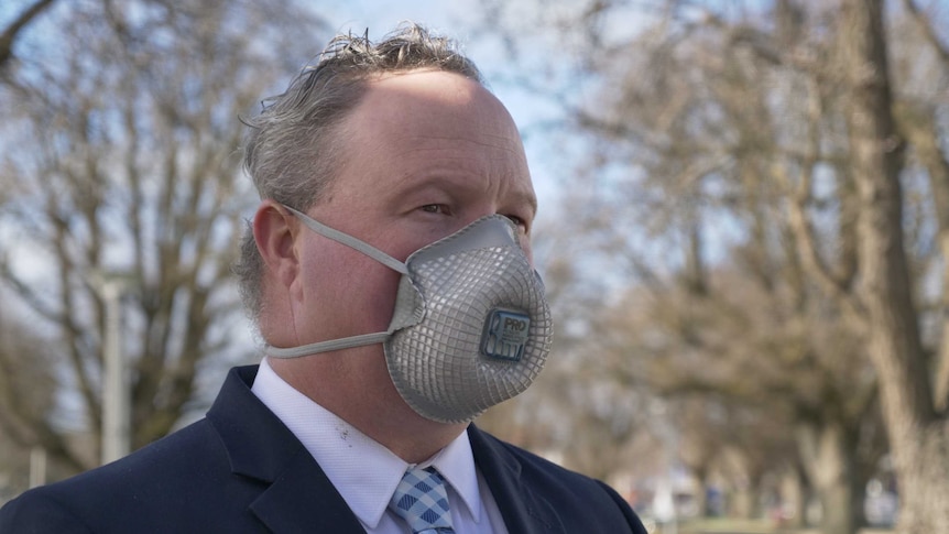 A man in a suit wearing a face mask.