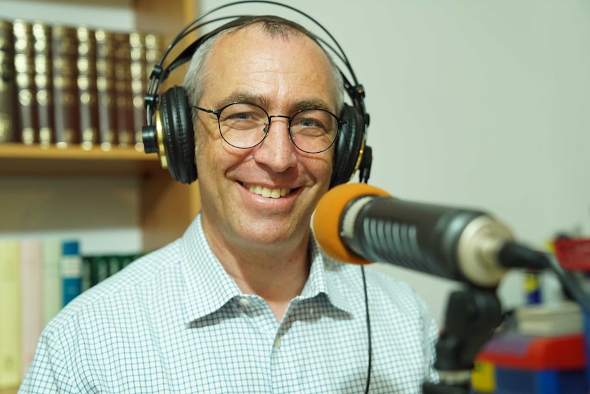 A man wearing headphones sits in front of a microphone