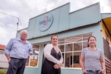 A man and two women stand outside a 1930s renovated shop.