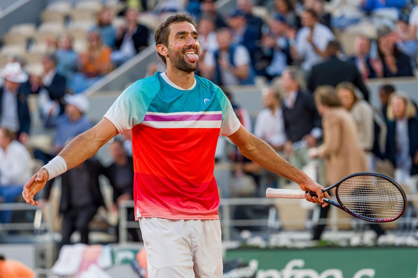 Marin Cilic celebrates his win over Andrey Rublev at the French Open by sticking his tongue out and holding his hands open wide