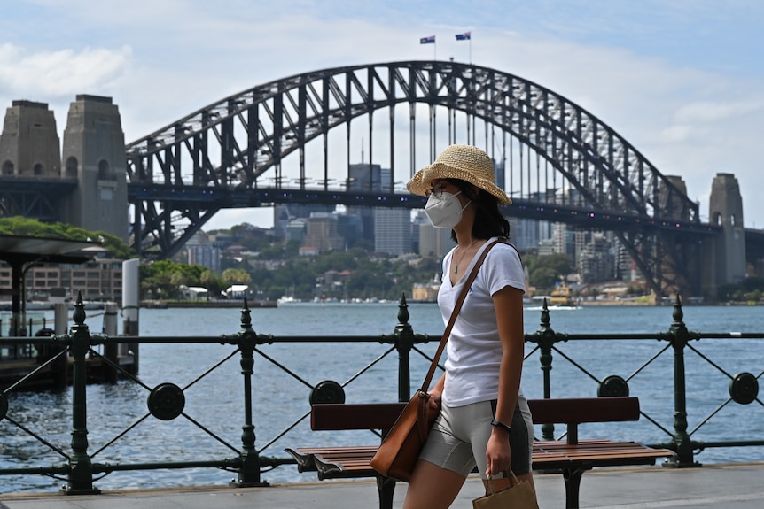 Woman walks past Sydney Harbour Bridge