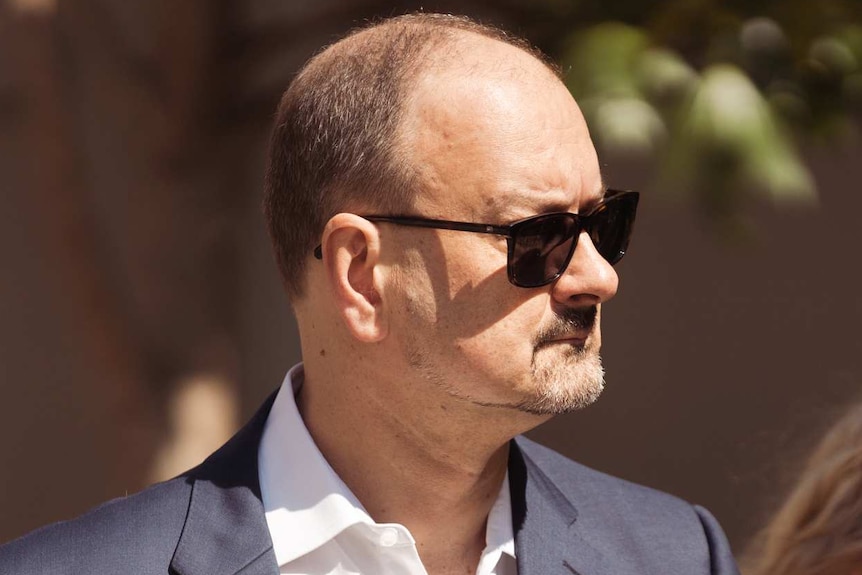 A lawyers dressed in a suit wearing sunglasses arrives at court.