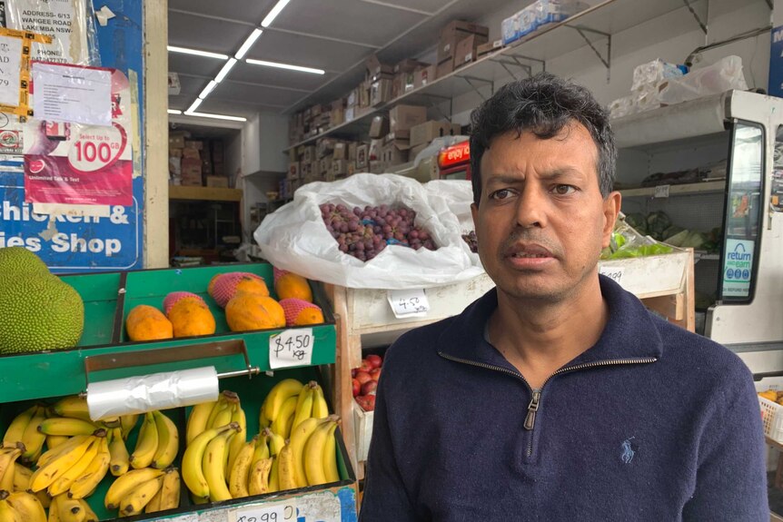 a man looking concerned in front of a grocer