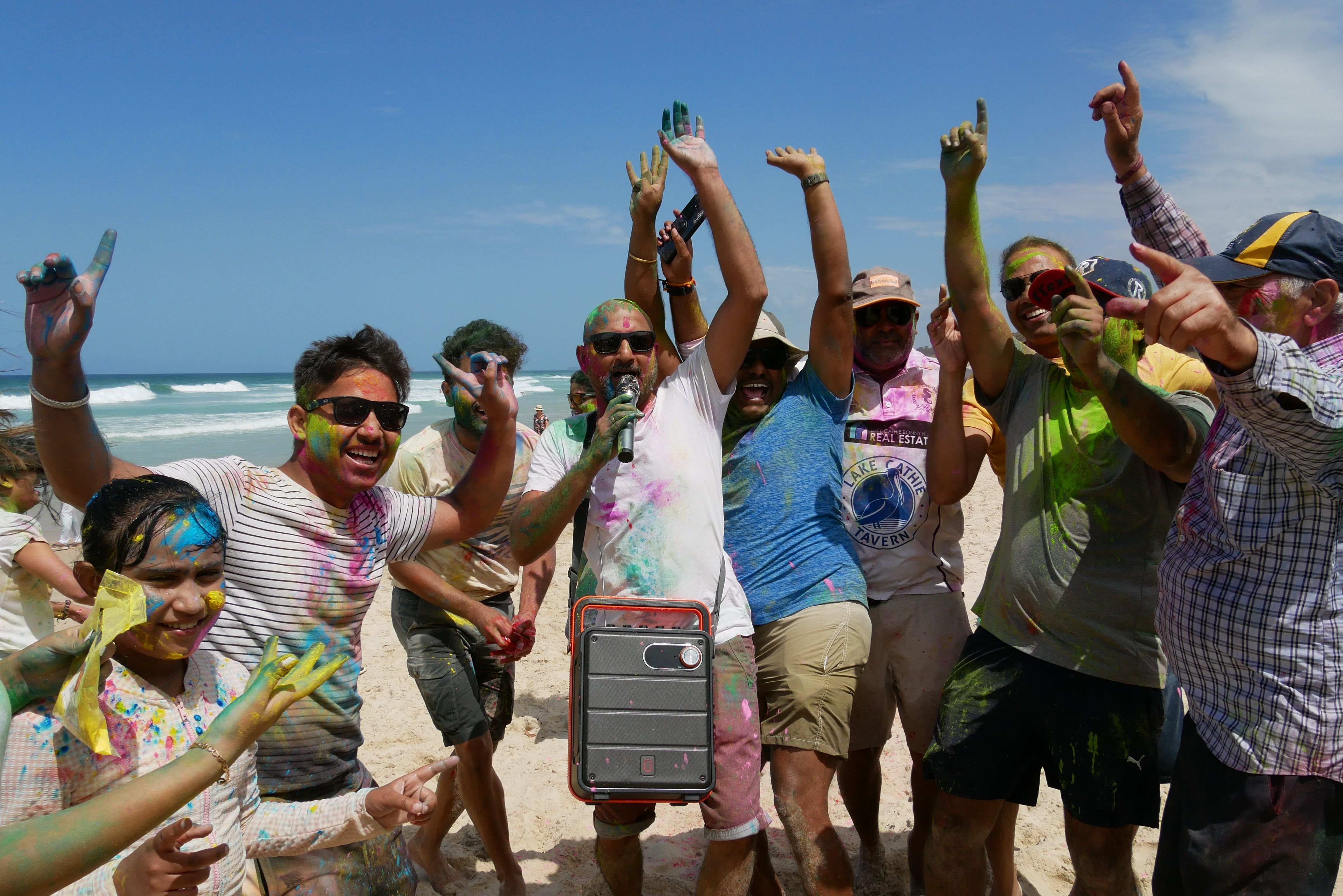 Group of people dance and sing together on the beach