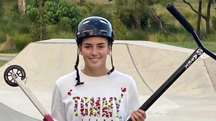 Bianca standing in a skate park, holding her scooter
