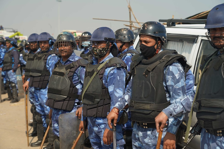 Riot police wearing helmets and bulletproof jackets while holding canes.
