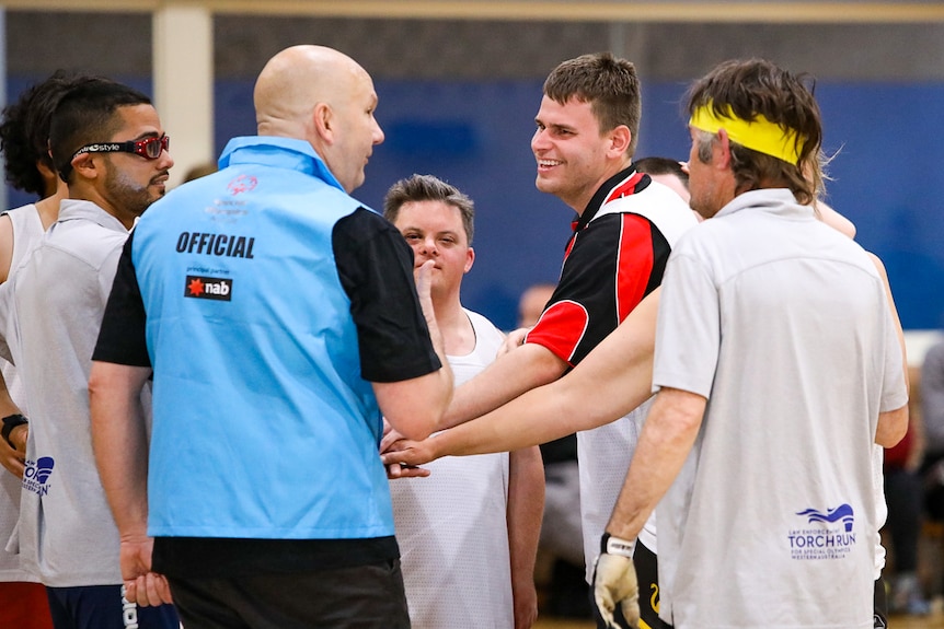 Players gather around an official on the basketball court.