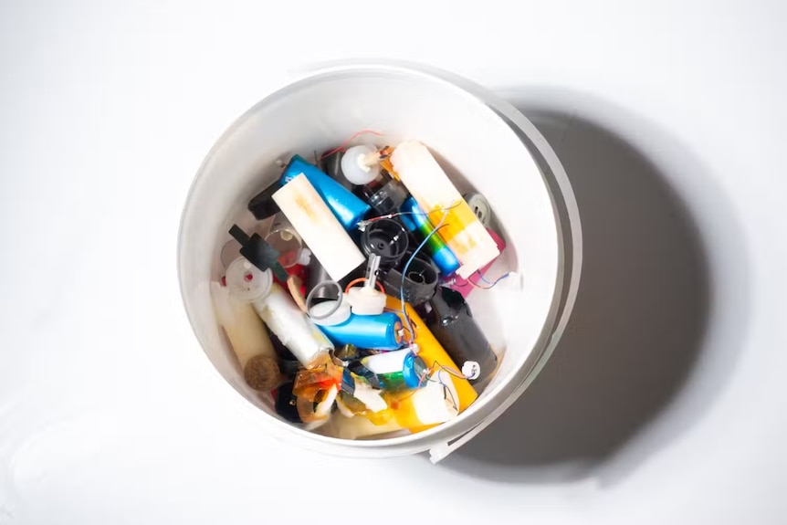 A container of colourful vape parts: batteries, wires, cartridges and plastics