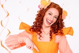 Emma Watkins in a bright orange dress performs the sign for twirl.