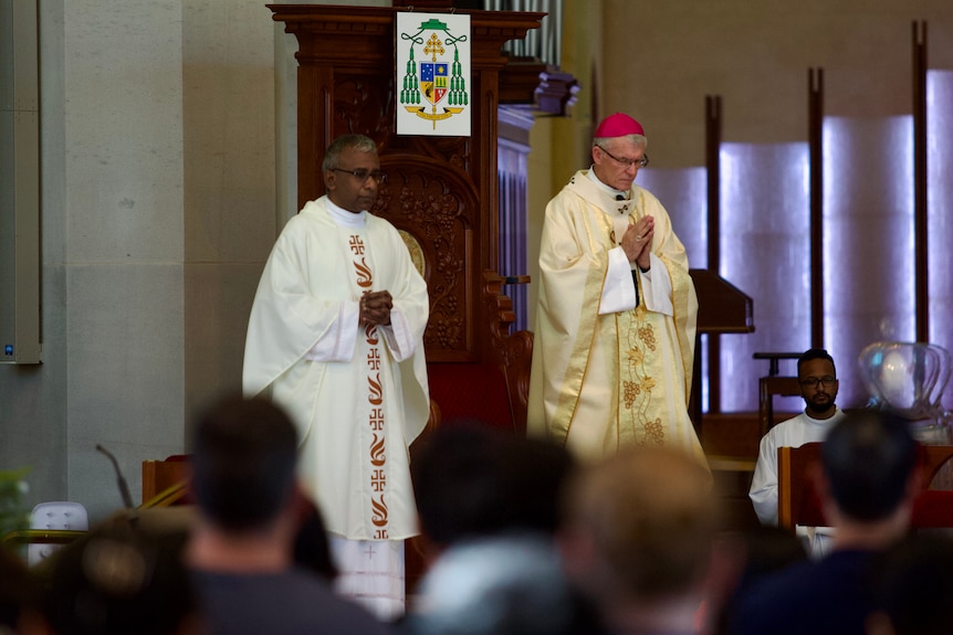 A mid shot of Catholic Archbishop of Perth Timothy Costelloe standing in church next to another man at a Christmas mass.