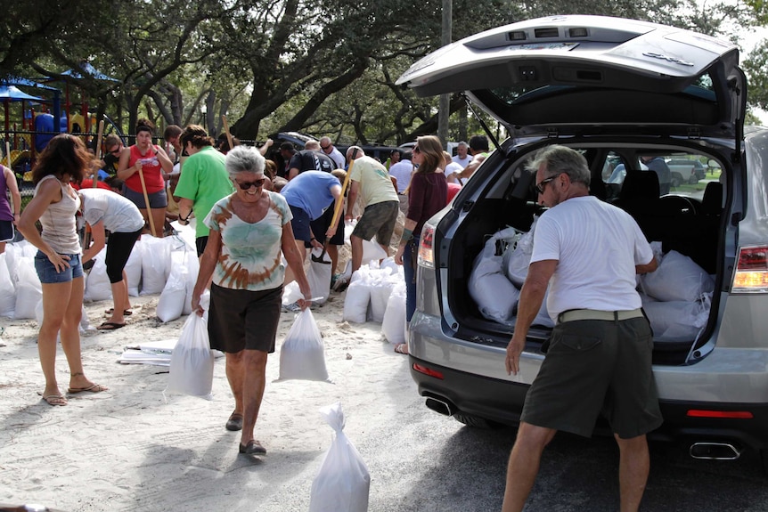 People carry sand bags as they prepare for a hurricane.