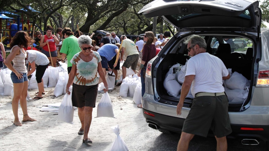People carry sand bags as they prepare for a hurricane.