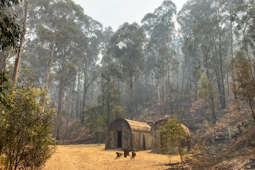 Two small buildings surrounded by burnt bushland.