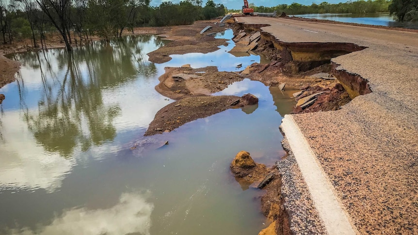 A collapsed section of road, with water on the left.