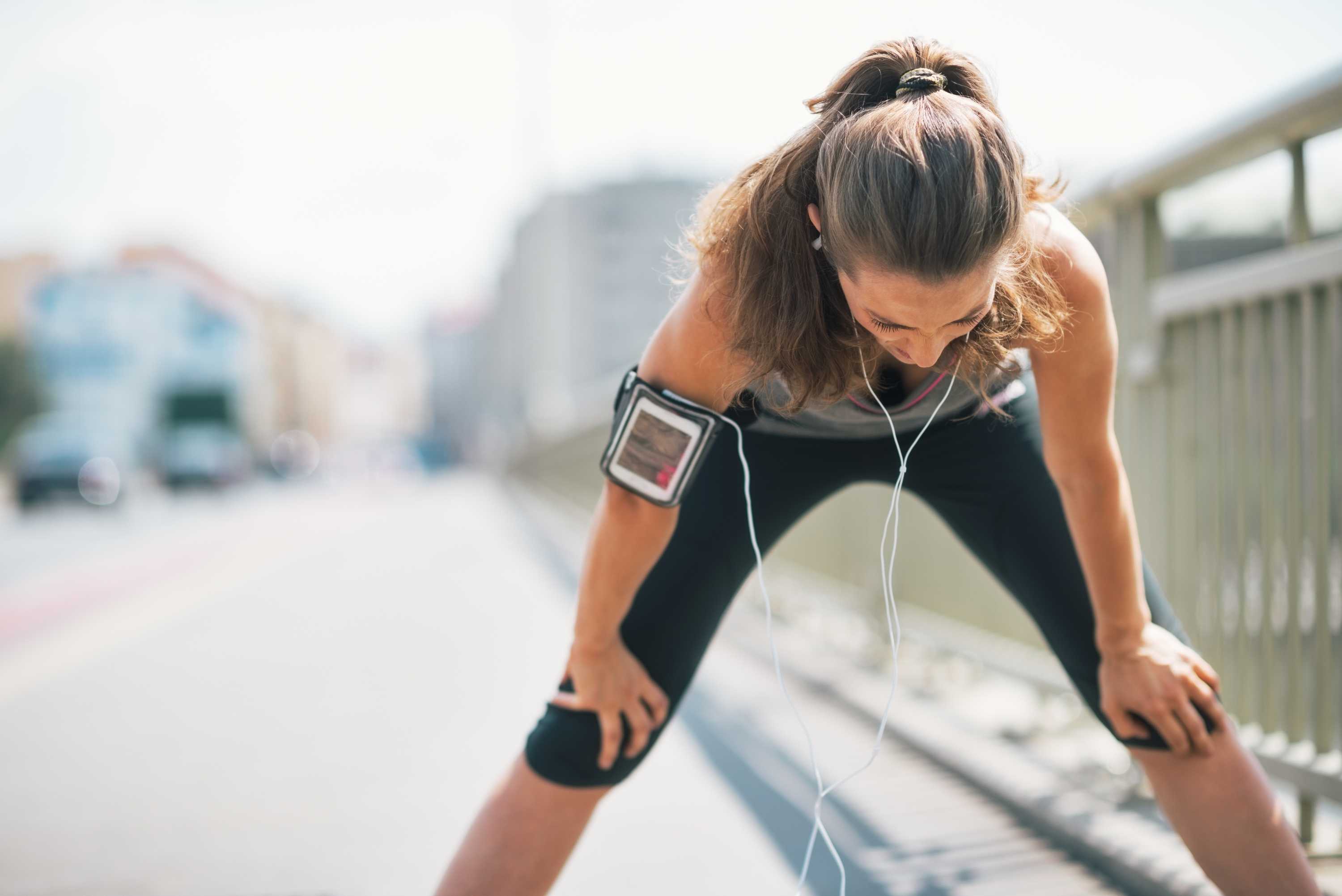 Woman leans over and catches her breath while exercising.