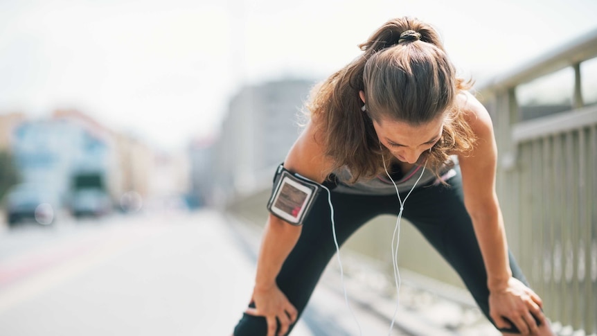 Woman leans over and catches her breath while exercising.