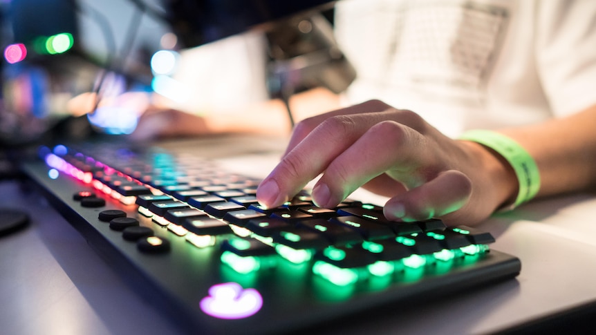 Photo of two hands typing at a multi-coloured gaming keyboard. 
