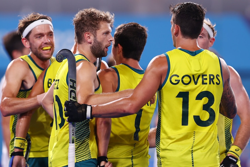 Five Australian men's hockey players embrace each other as they celebrate a goal at the Tokyo Olympics.