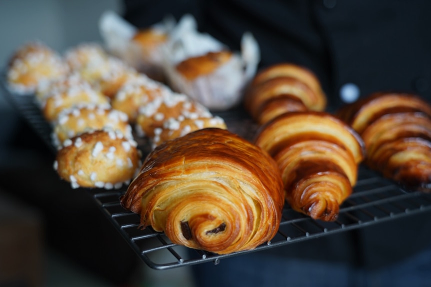 A close-up shot of croissants and French pastries on an oven rack.