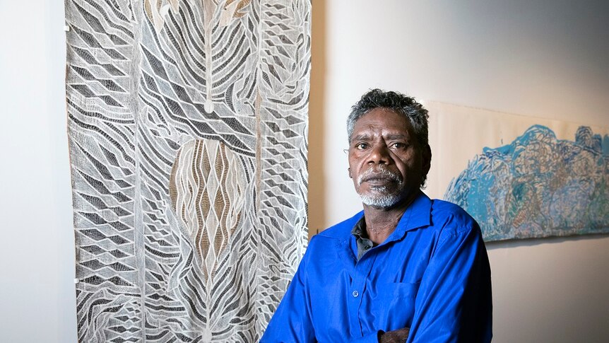 Napuwarri Marawili stands beside his art
