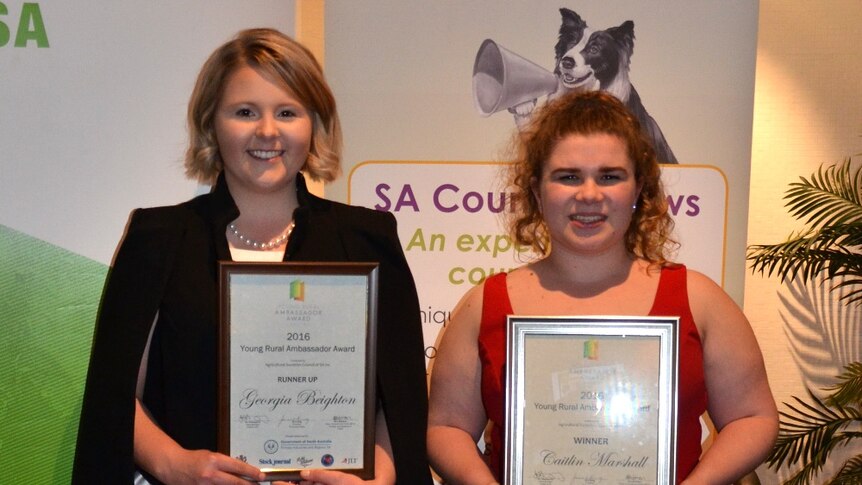 Two young women holding framed certificates.