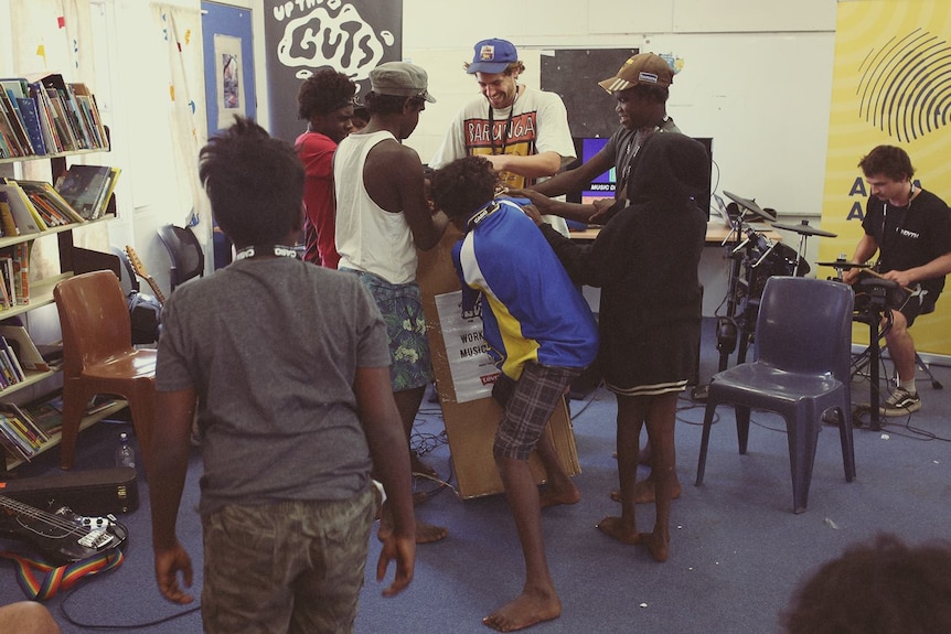 Kids stand around a box in a classroom.