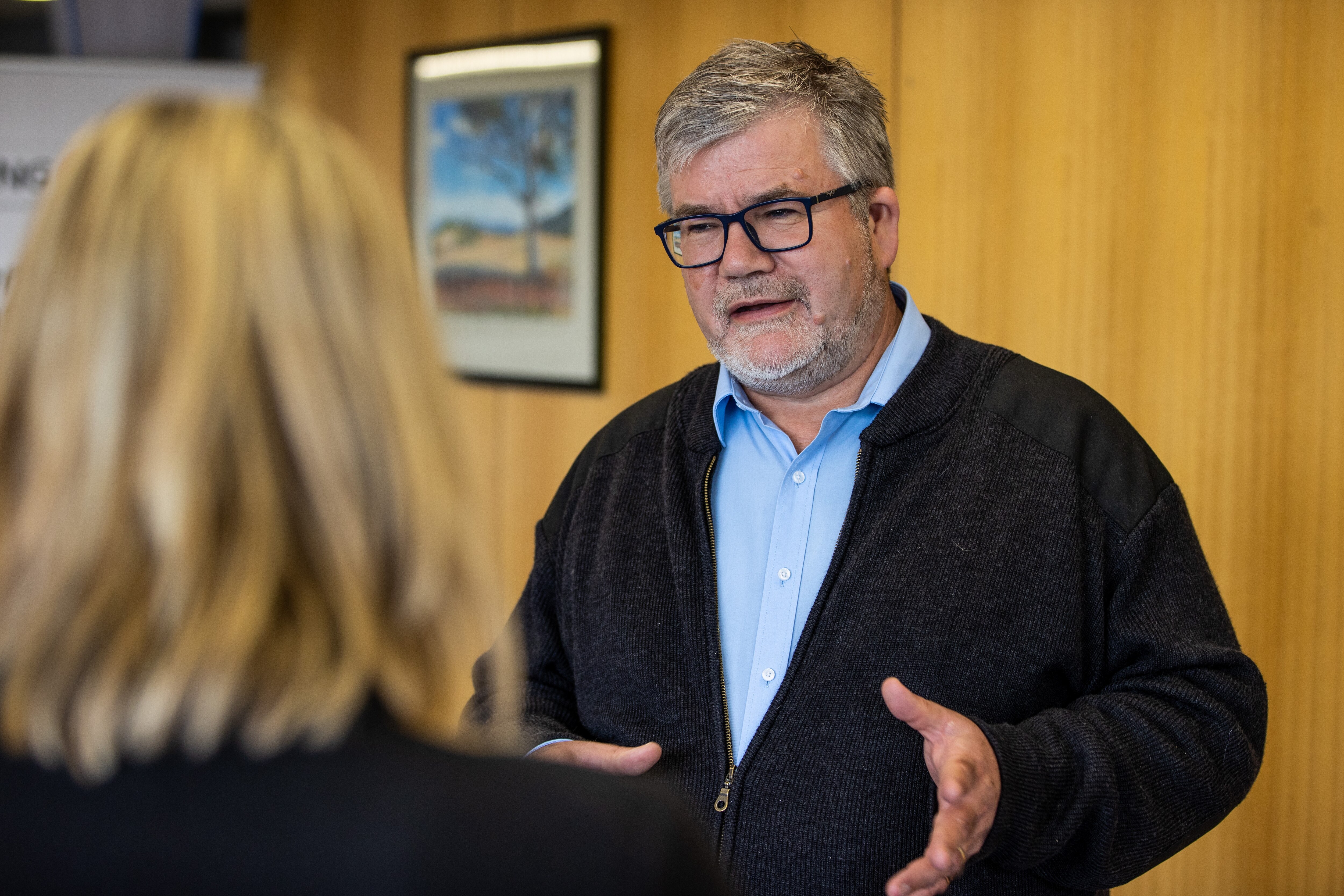 Professor James Vickers speaks to a woman who is out of focus and has her back to the camera
