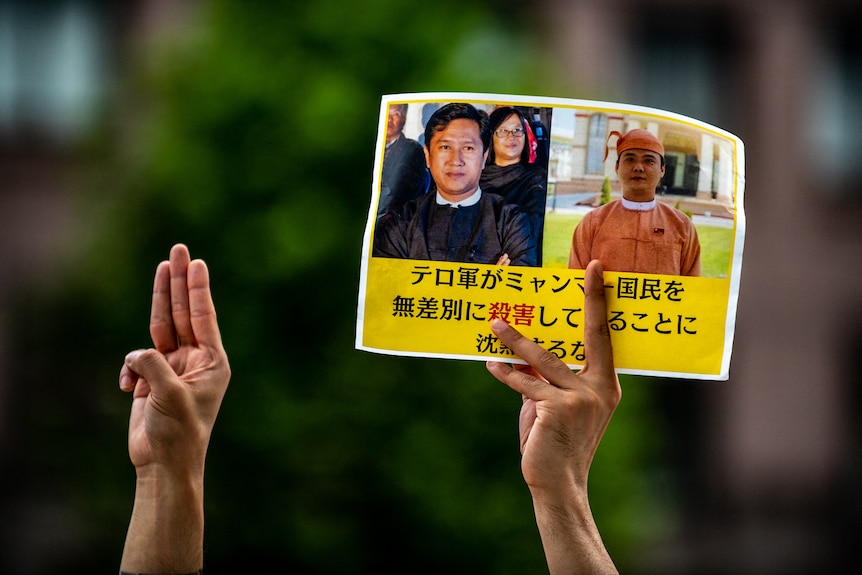 A three-finger salute and picture of two men killed with Japanese writing on A4 paper