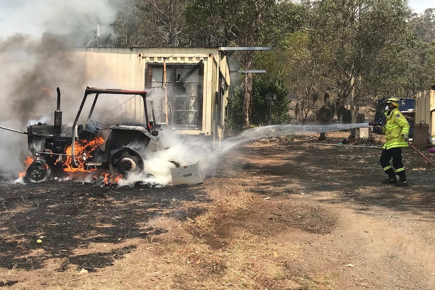 A man hosing down a burning tractor