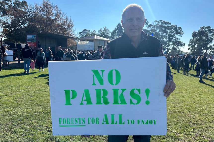 Graham holding a sign that says no Parks! Forests for all to enjoy.