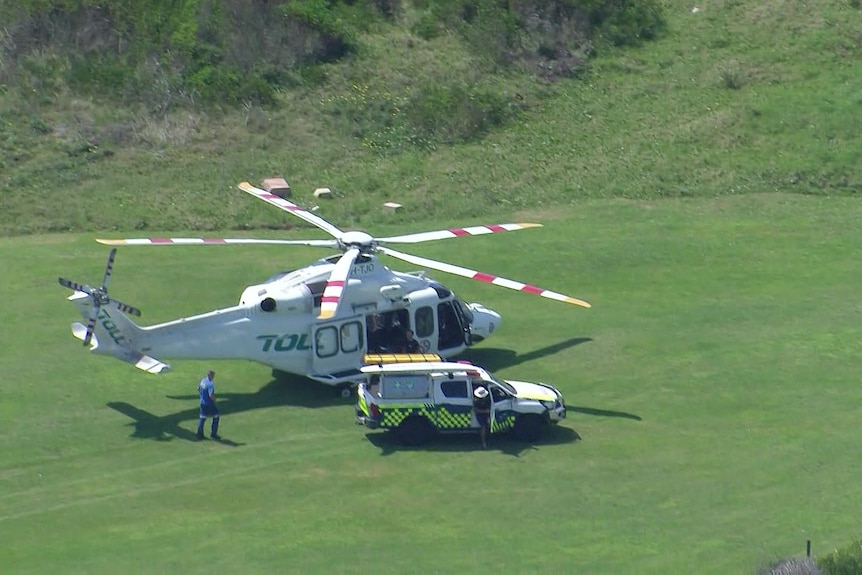 an ambulance on the grass parked near an emergency helicopter
