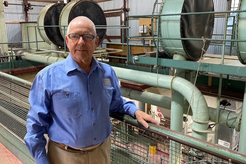 man stands in front of a fence and pipes