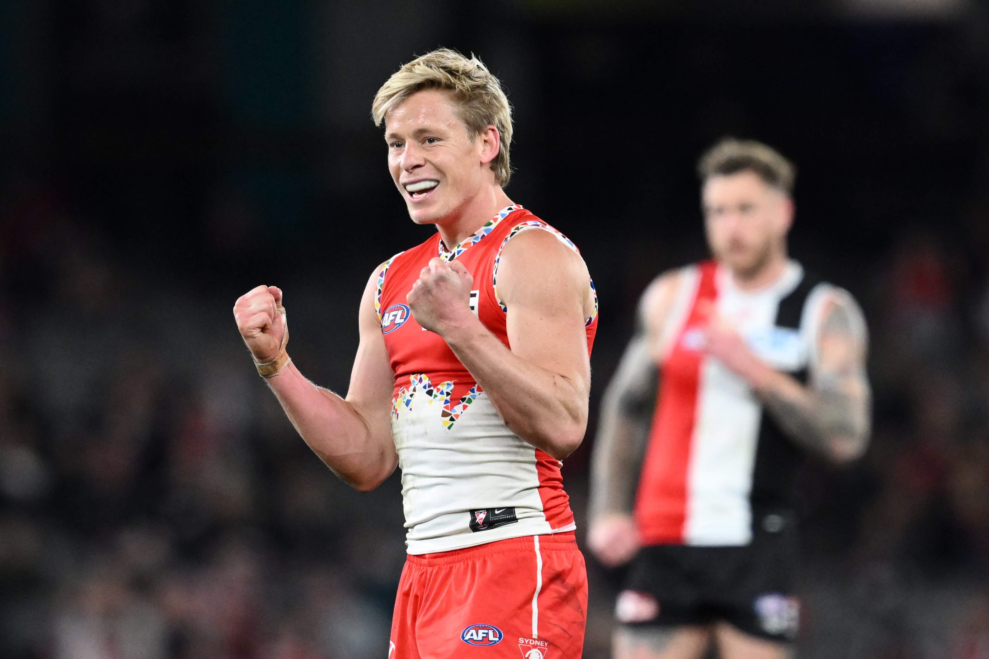 A man in a Sydney Swans uniform raises his fists in celebration. 