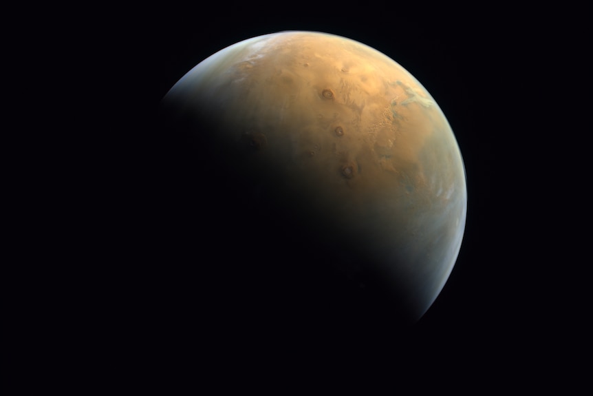 A space agency image of Mars with half of the planet in shadow. 