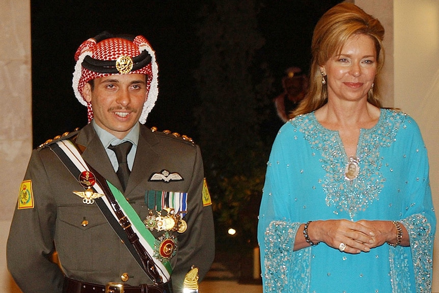 Le prince de Jordanie Hamzah, vêtu d'un uniforme militaire, se tient aux côtés de sa mère, la reine Noor, qui porte une robe bleu clair.