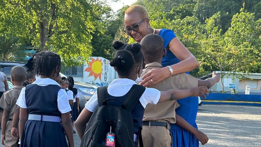 Education Minister hugs students walking out of a primary school 