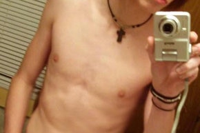 A pic of a very skinny teenage boy taking a photo of himself in the mirror with no shirt on (face cropped out). (blogspot.com)