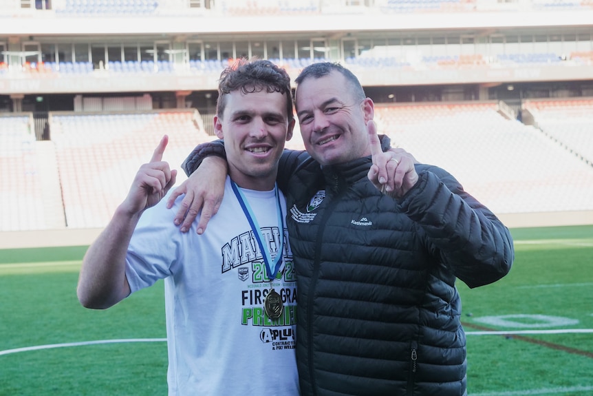 two men posing after their team won a local rugby league grand final